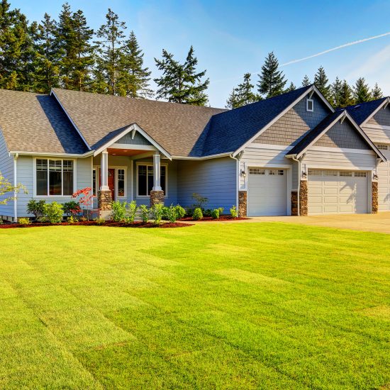 Blue craftsman home with double garage and manicured lawn