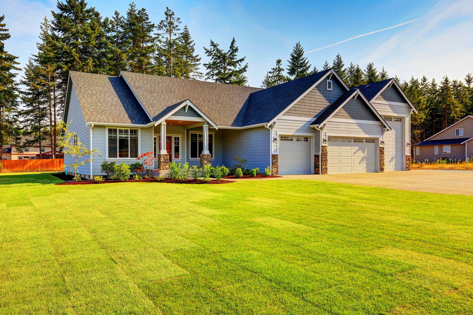 Blue craftsman home with double garage and manicured lawn