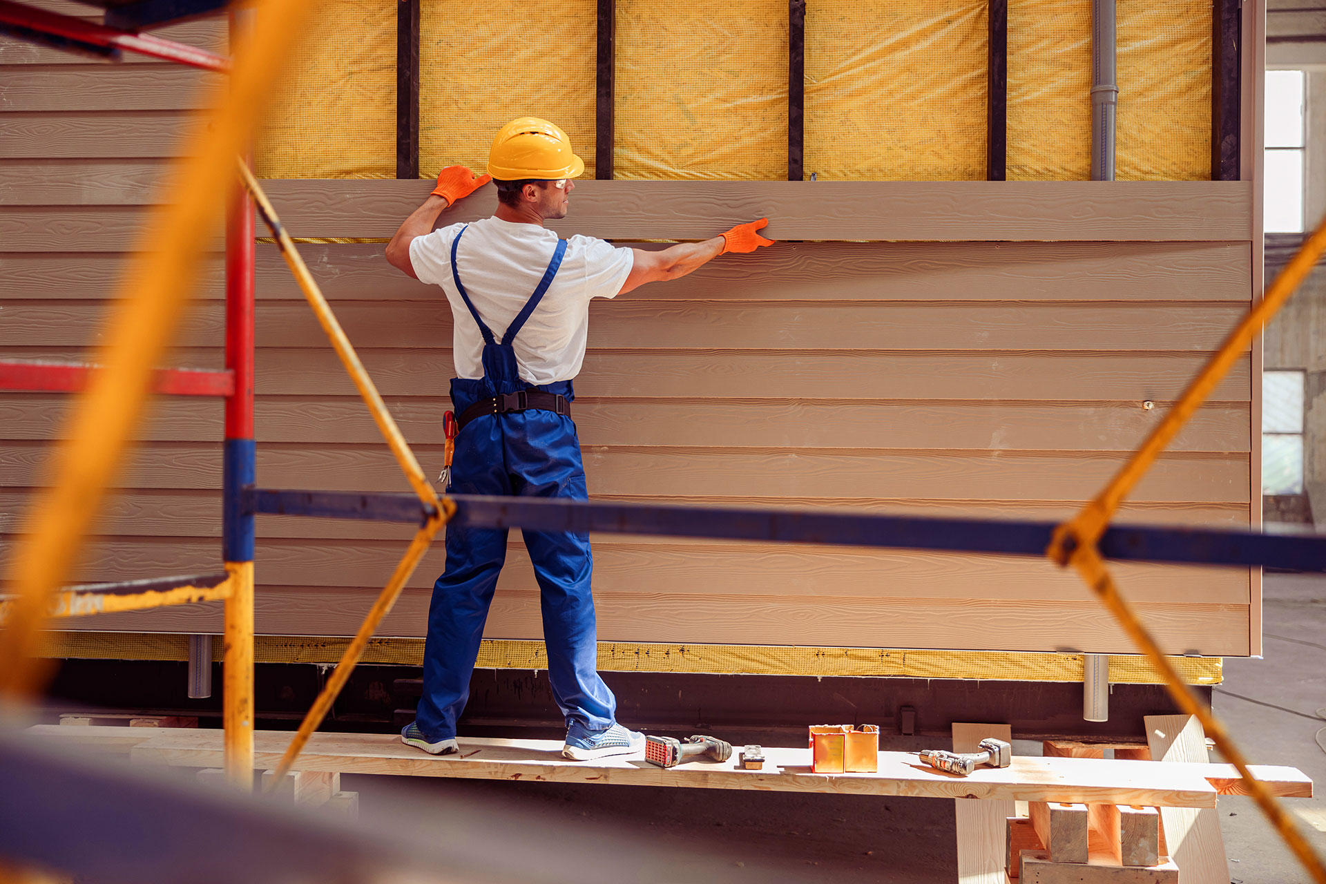 Worker installing vinyl siding panels on residential exterior wall